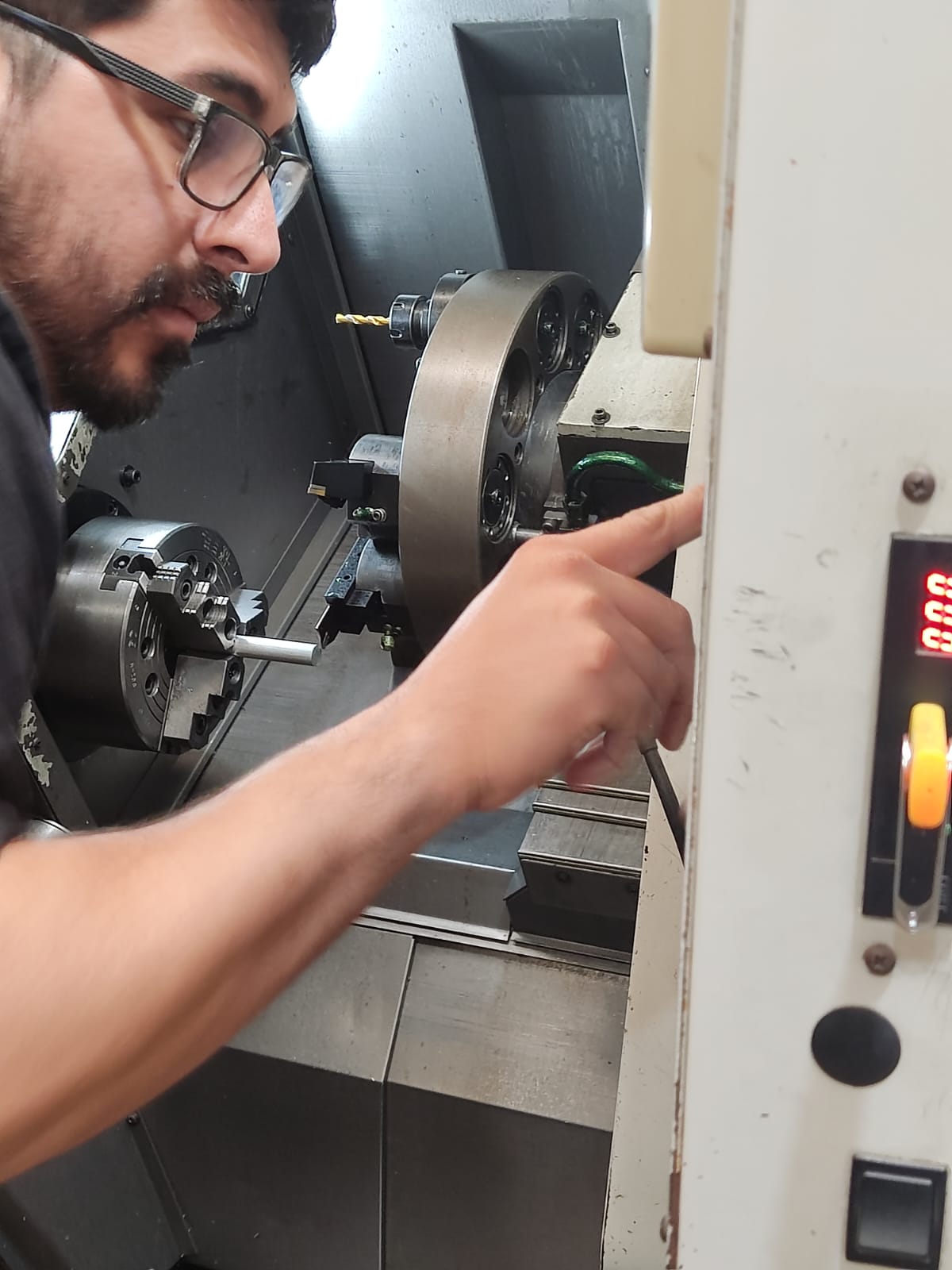 Alumno operando un torno CNC en el taller